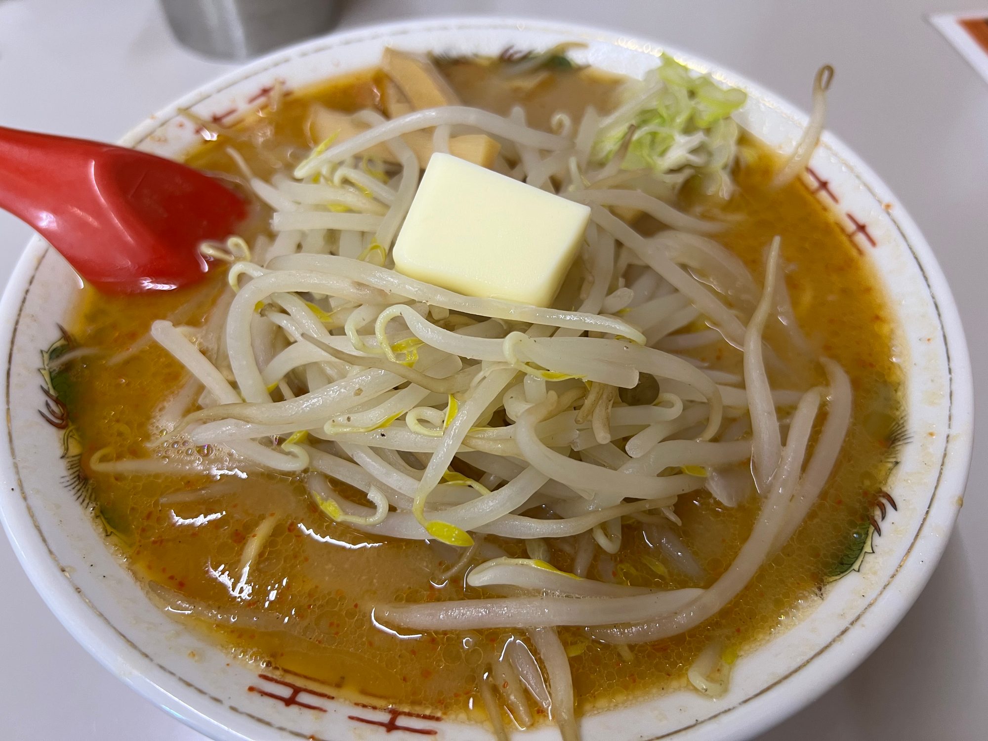 よし乃のみそラーメン。もやしたっぷりにバターがのり、赤いレンゲが添えられている