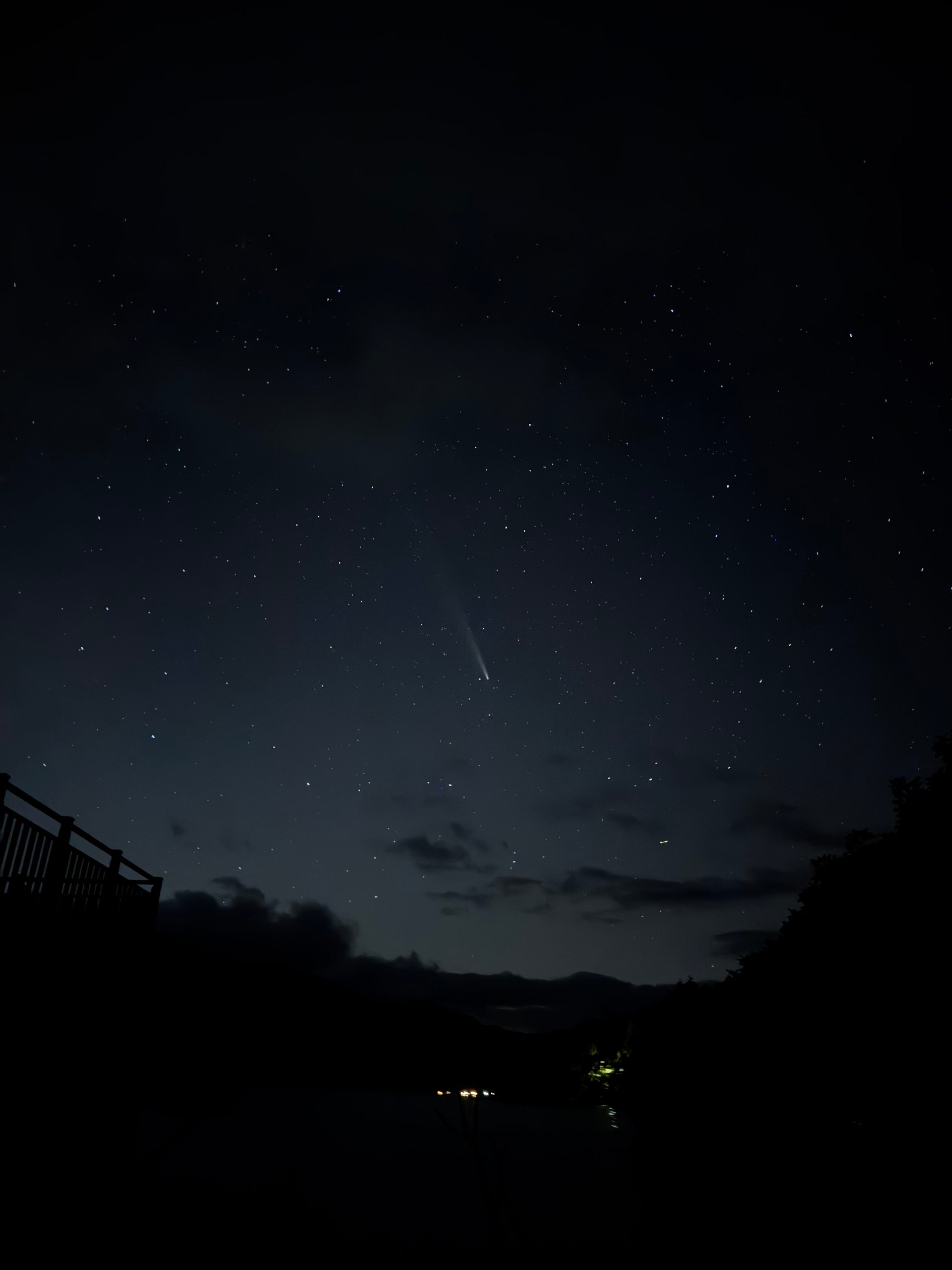 星空にのびる紫金山・アトラス彗星の淡い尾。手前に手すりと木のシルエット