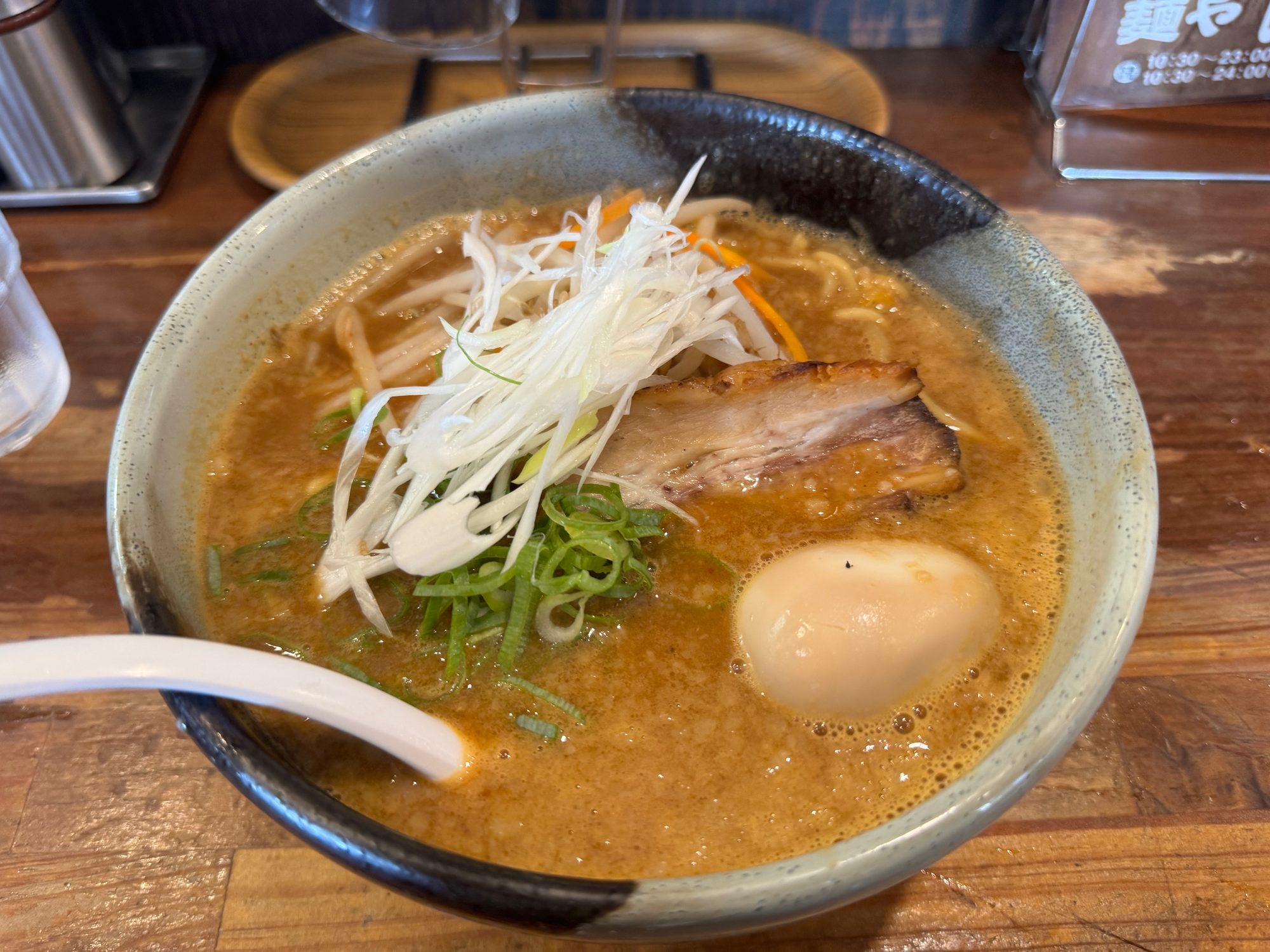 味噌ラーメンの丼。白髪ねぎともやし、炙りチャーシュー、半熟の煮卵、青ねぎがのった濃厚な味噌スープ