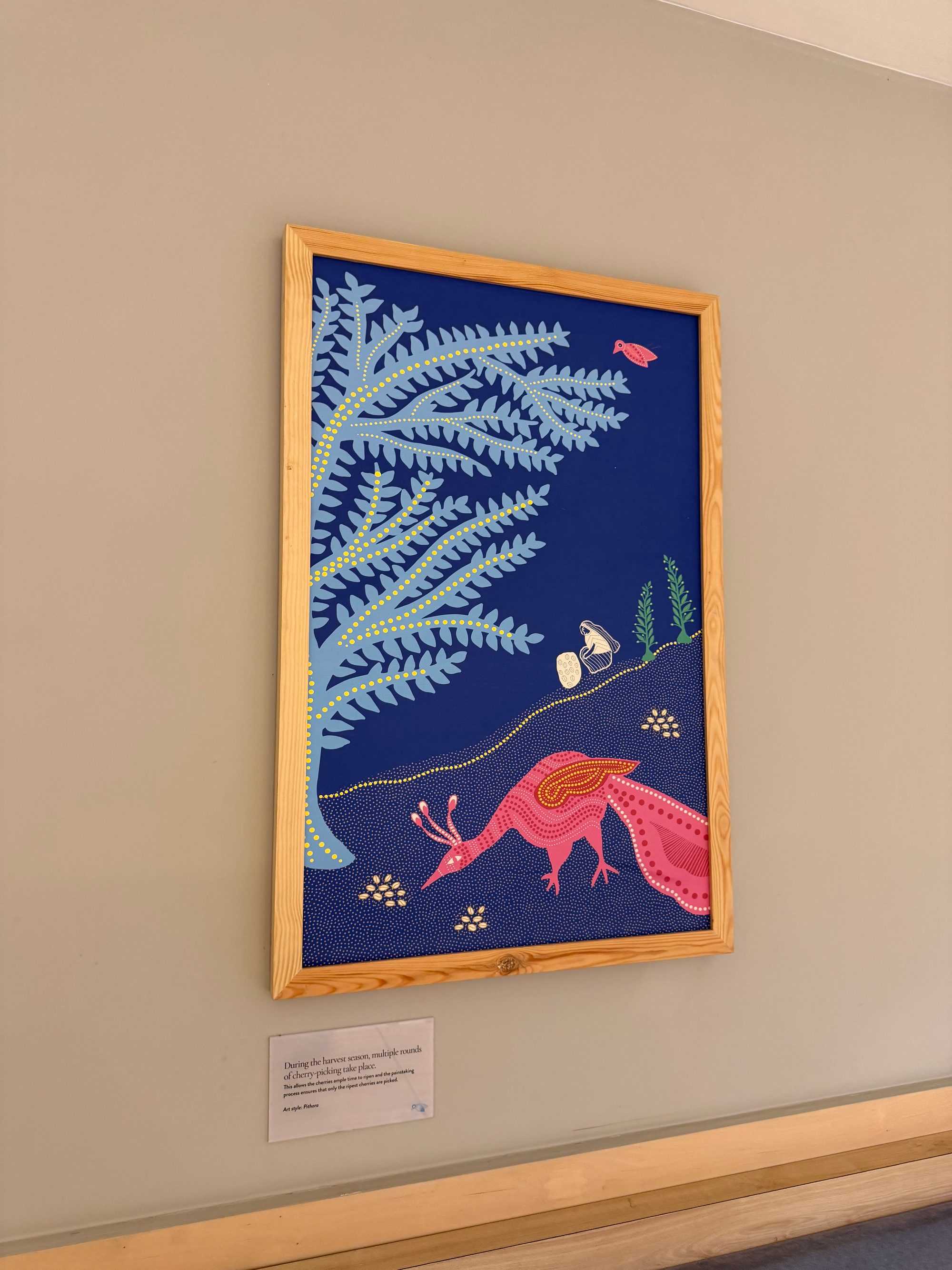 壁に飾られた、ピンクの鳥と珊瑚を描いた青いピチワイ調の額装絵画