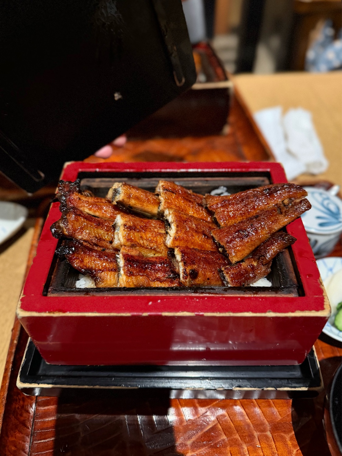 赤い漆塗りの重箱に並んだ艶やかな鰻の蒲焼き